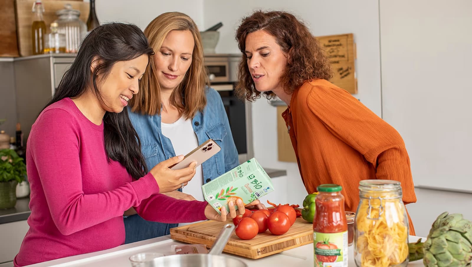 Three people in a kitchen looking at a product together with the Xtra app open on a phone